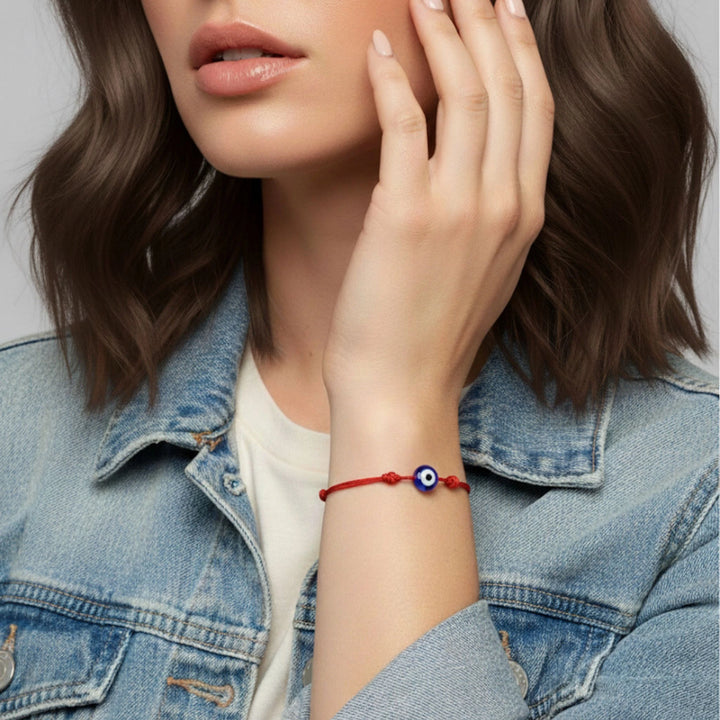 Person wearing a red bracelet with a blue eye design on a neutral background