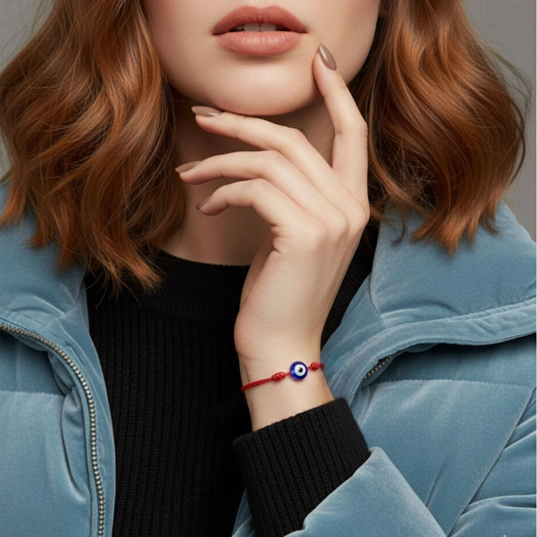 Person wearing a blue jacket with a close-up of their hand and bracelet featuring an eye design.