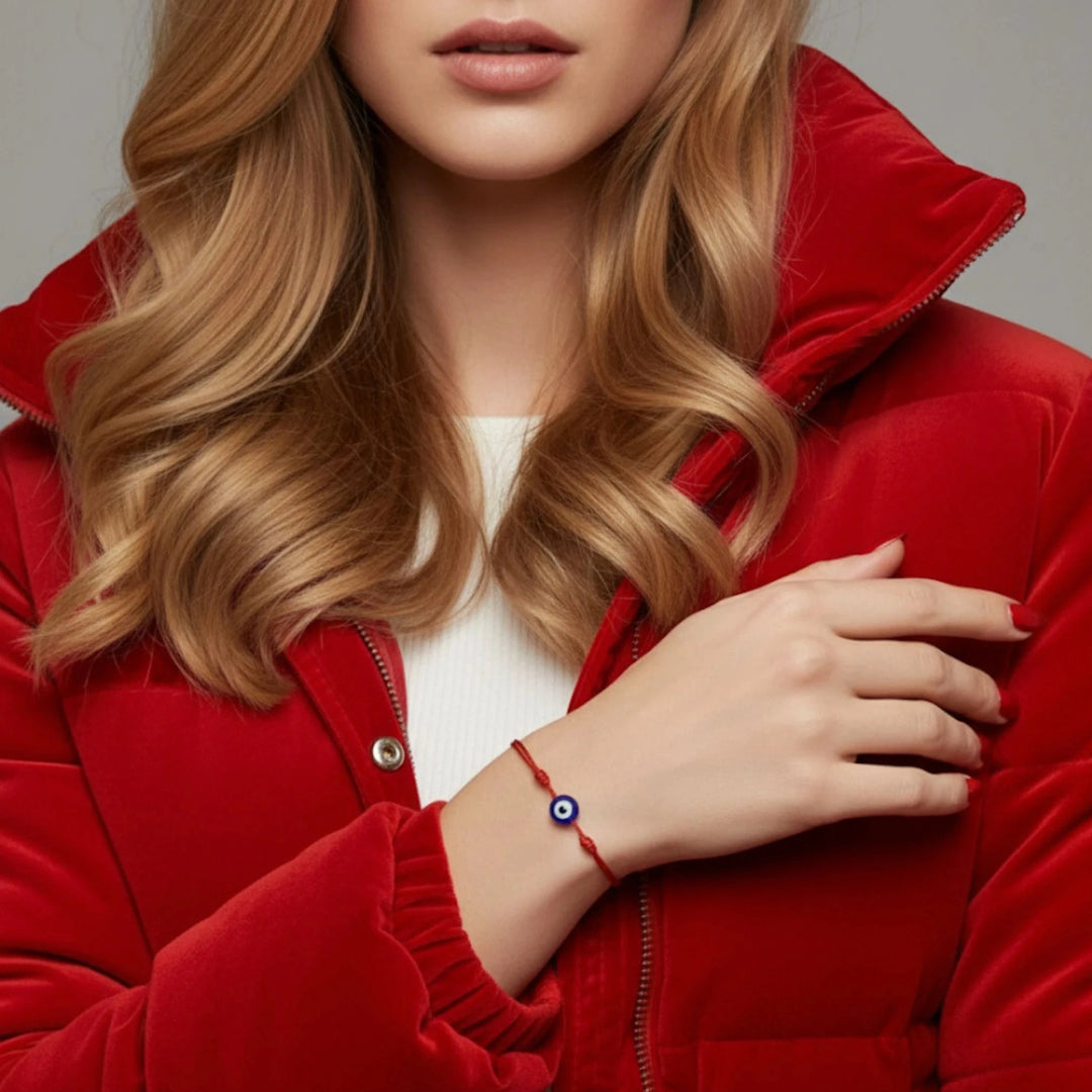 Person wearing a red jacket with a close-up of a hand wearing a red bracelet with an eye symbol.