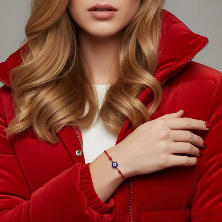 Person wearing a red jacket with a close-up of a hand wearing a red bracelet with an eye symbol.