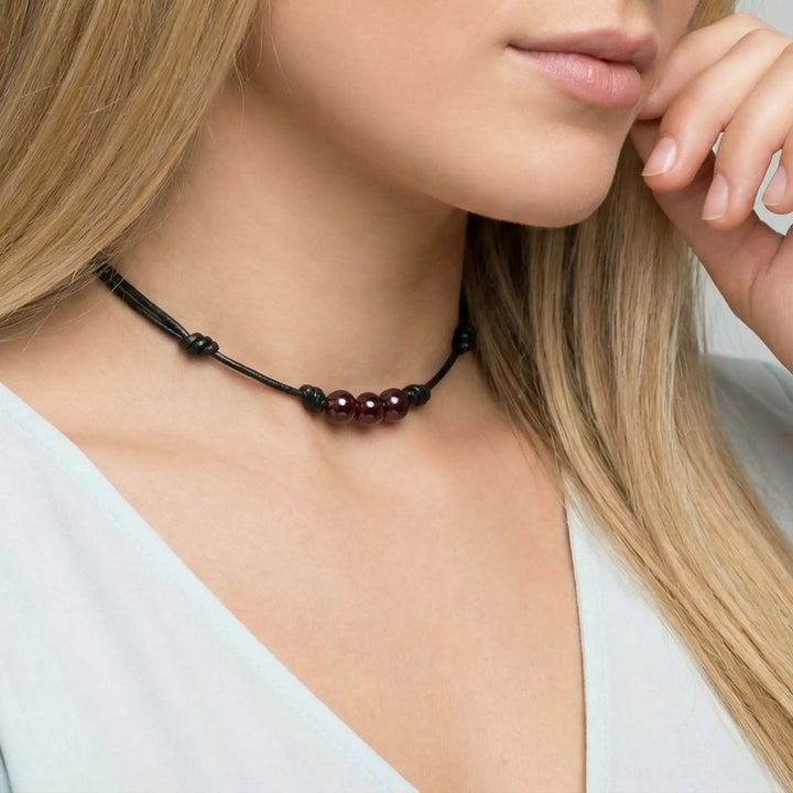 Necklace with red beads worn by a model on a plain background