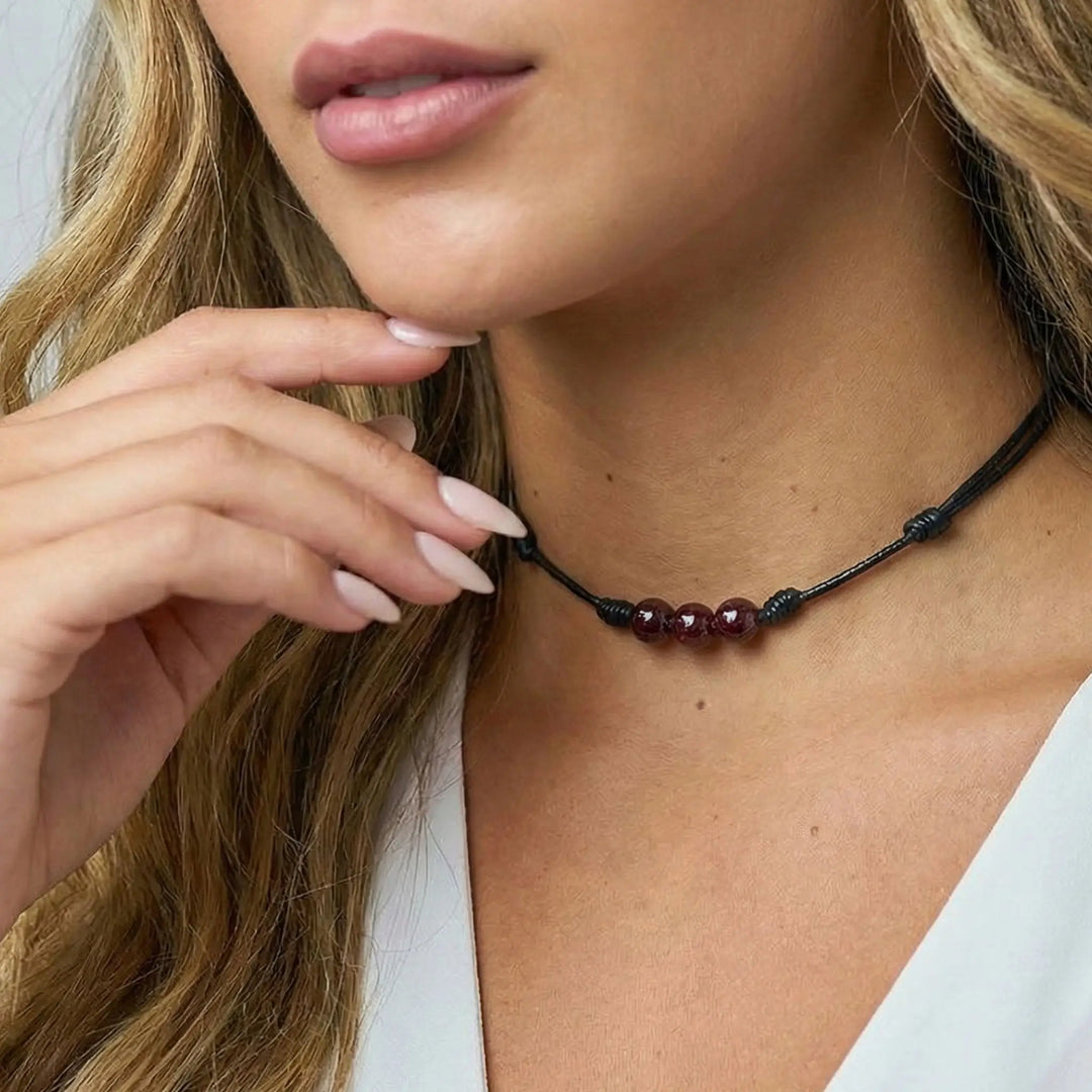 Close-up of a woman wearing a beaded necklace with a neutral background