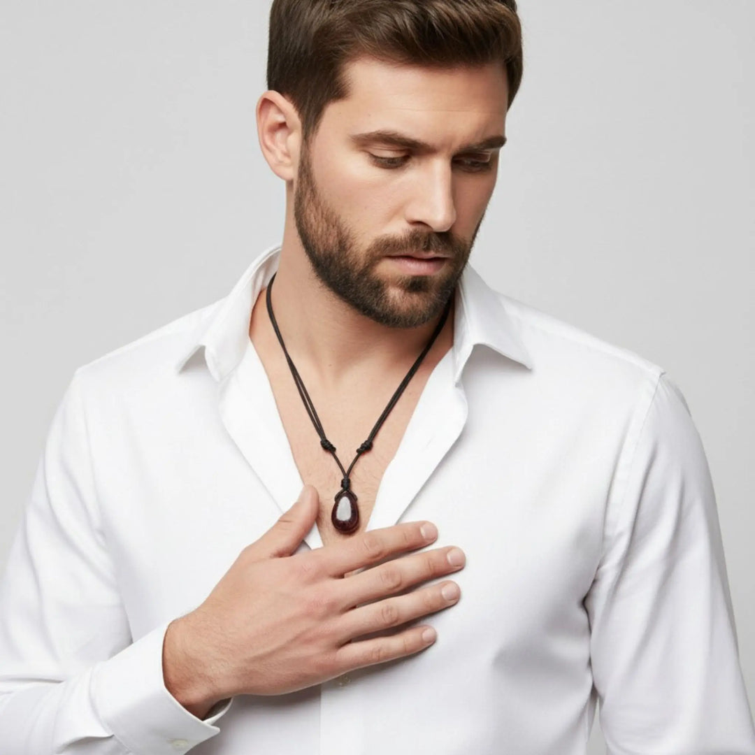 Man wearing a white shirt and necklace against a gray background