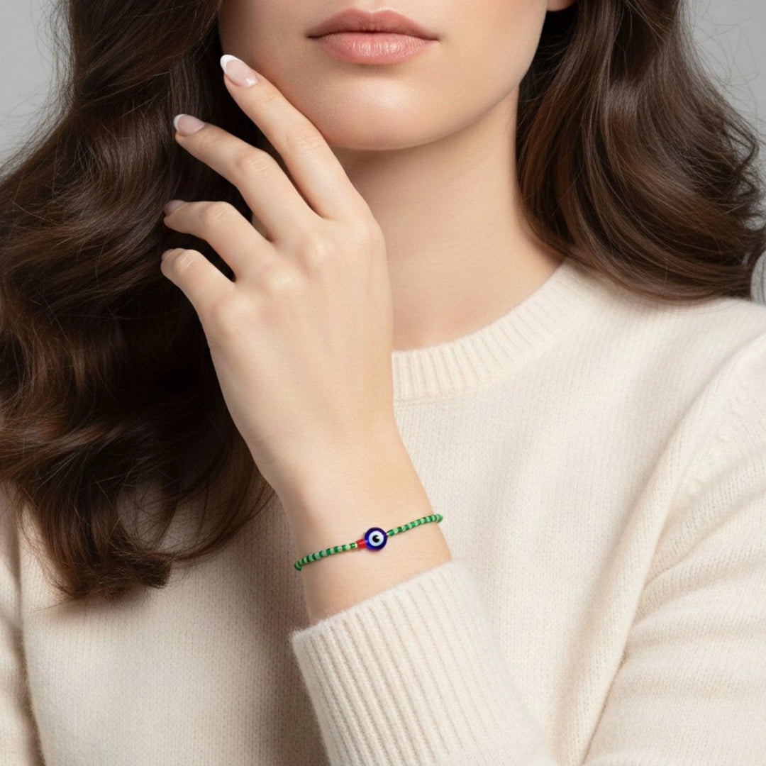 Woman wearing a bracelet with a blue evil eye charm on a neutral background