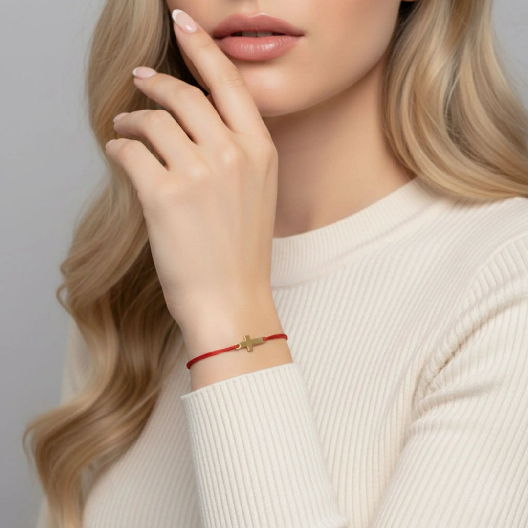 Woman wearing a red gold cross bracelet  on a neutral background