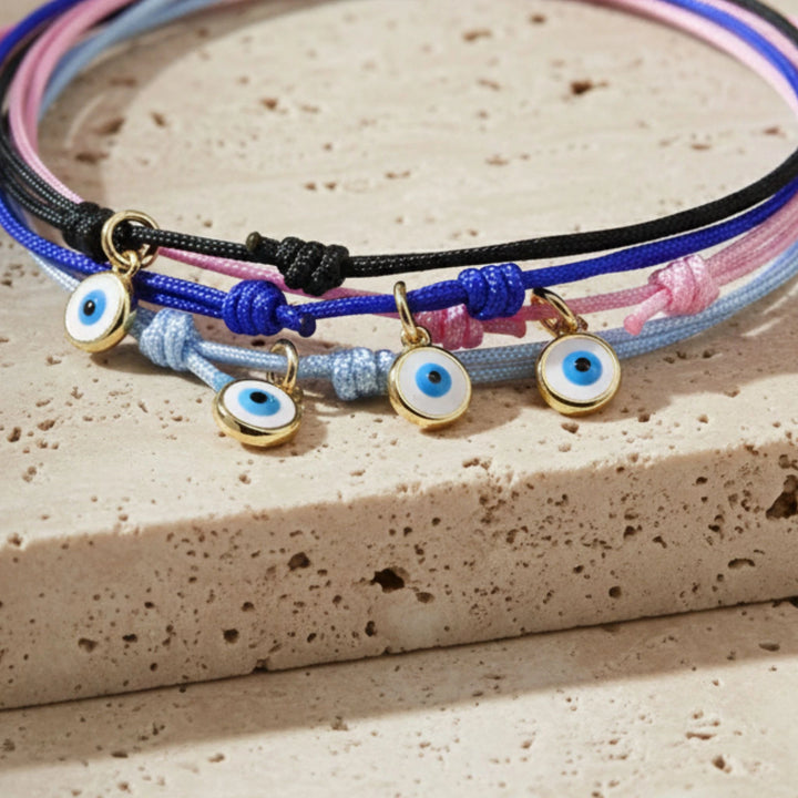 Colorful bracelets with evil eye charms on a textured surface