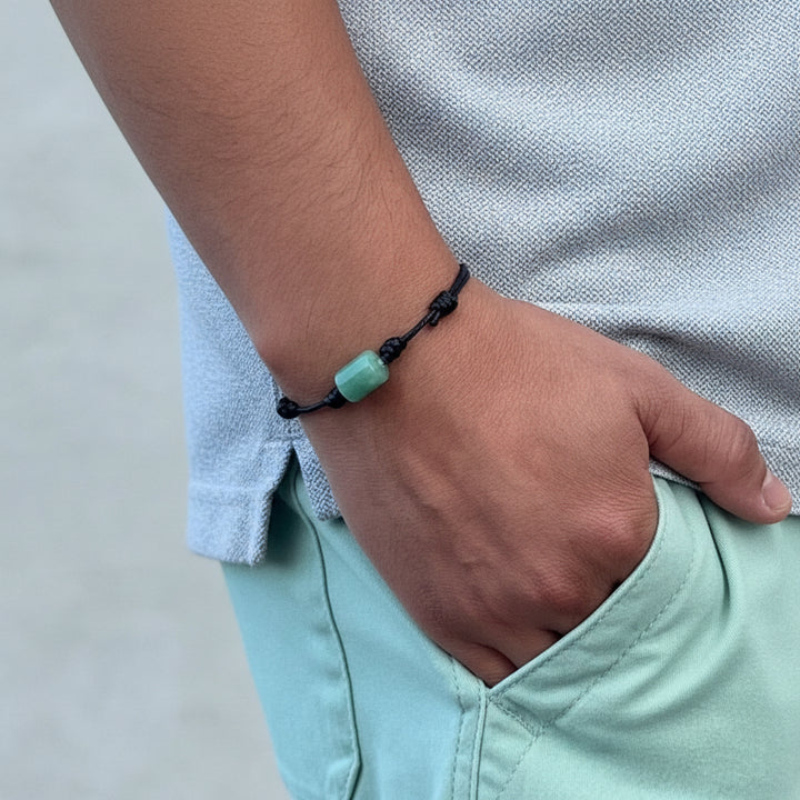 Close-up of green aventurine bracelet on black waxed cord.
