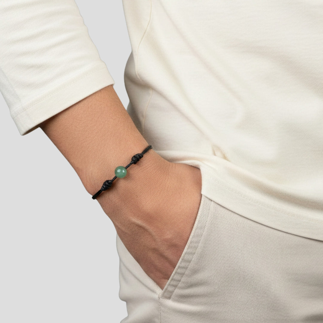 Person wearing green aventurine single bead bracelet on black waxed nylon cord.