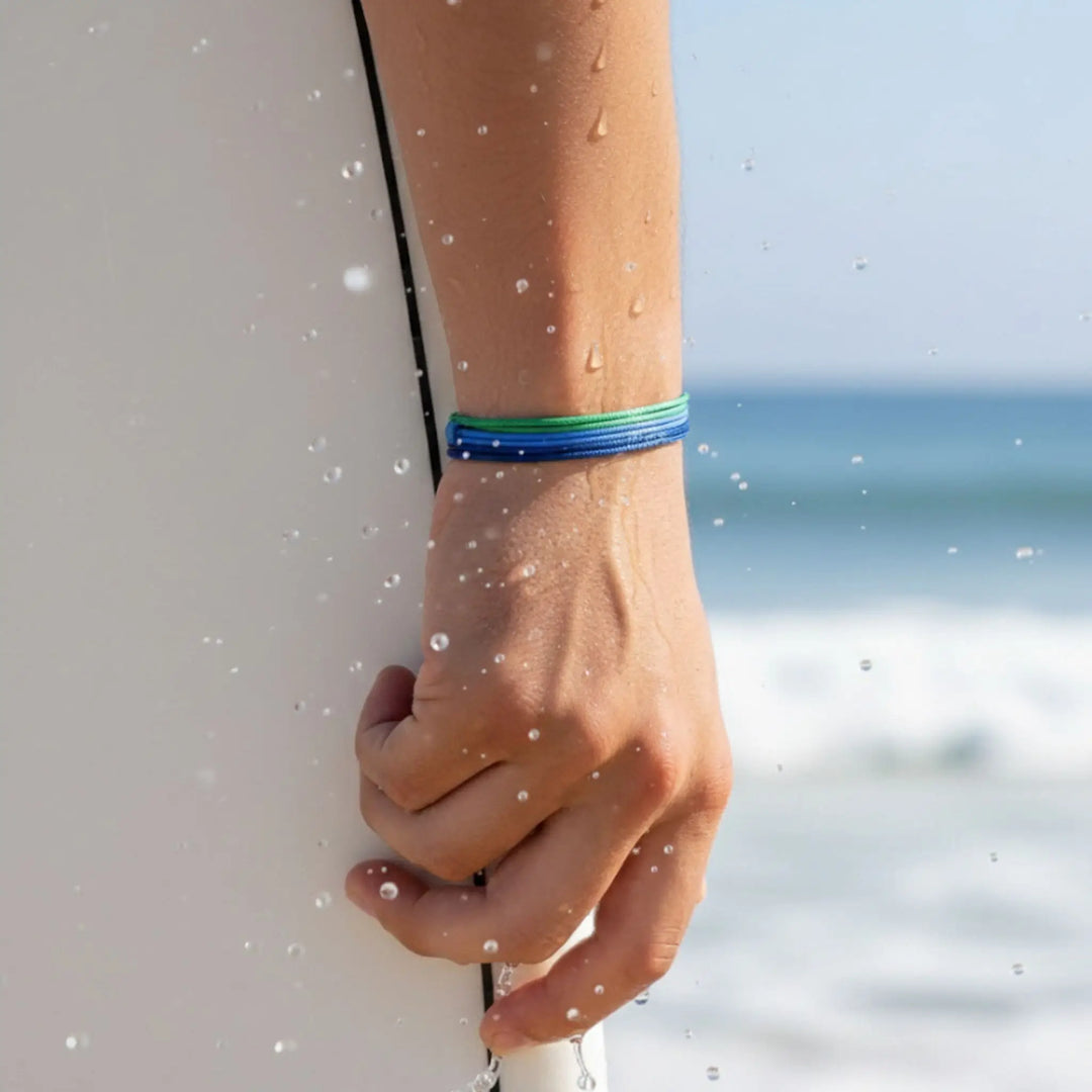 Hand holding a surfboard with a blurred beach background