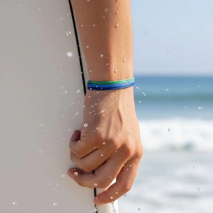 Hand holding a surfboard with a blurred beach background