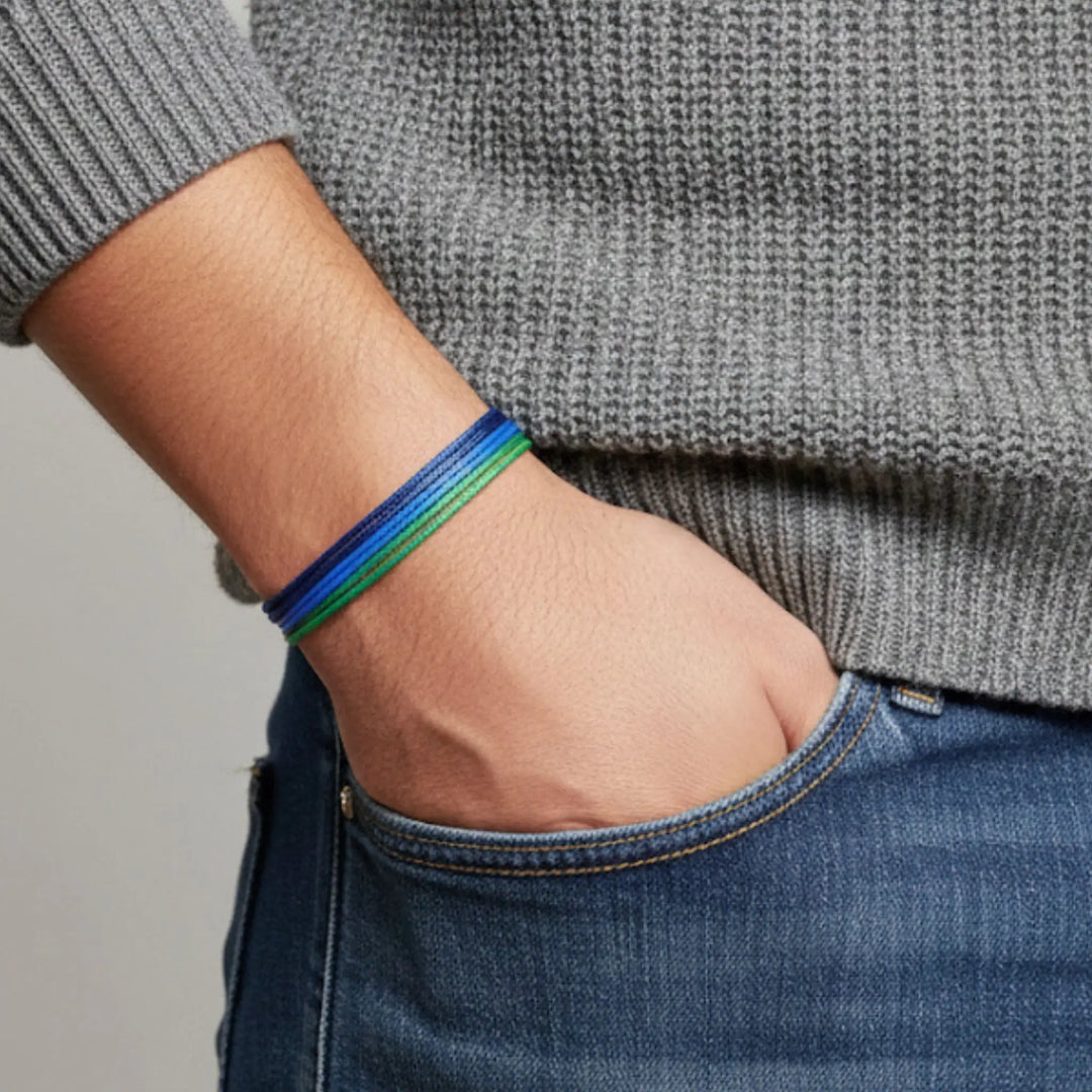 Person wearing a blue and green bracelet on a neutral background