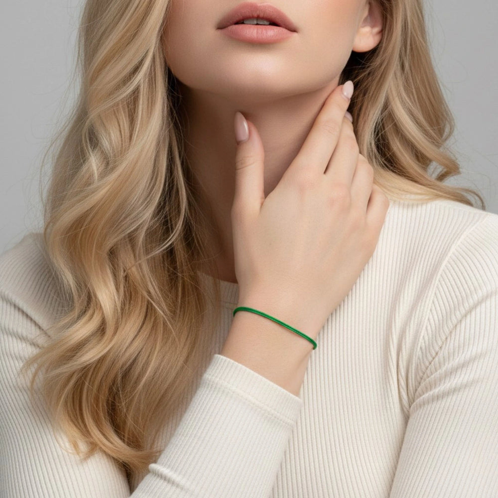 Woman wearing a green bracelet on a neutral background