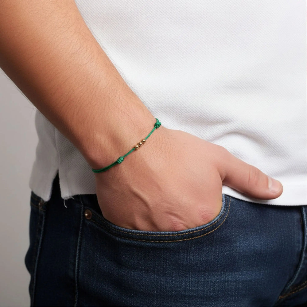 Person wearing a green bracelet on a plain background