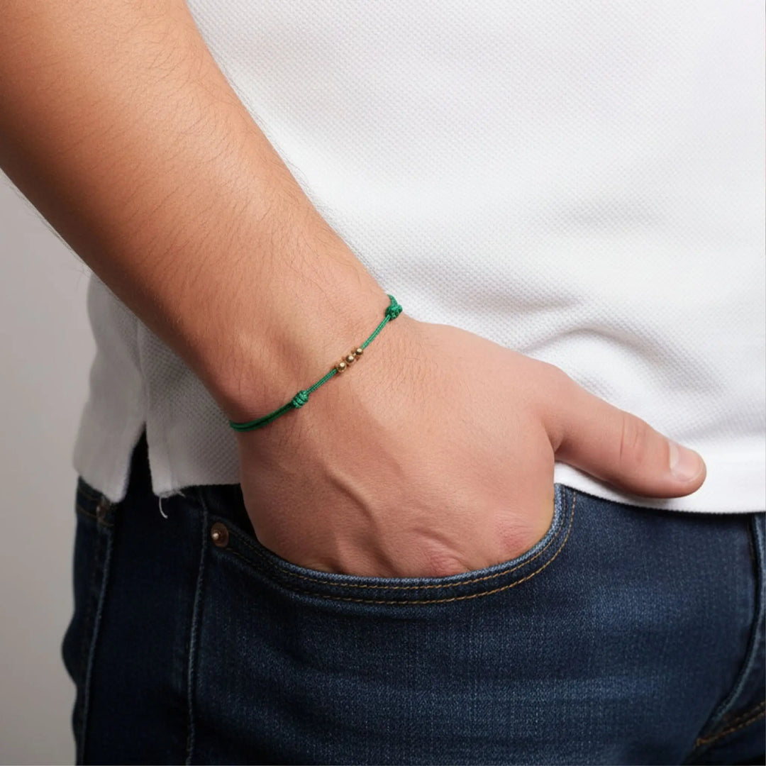 Person wearing a green bracelet on a plain background
