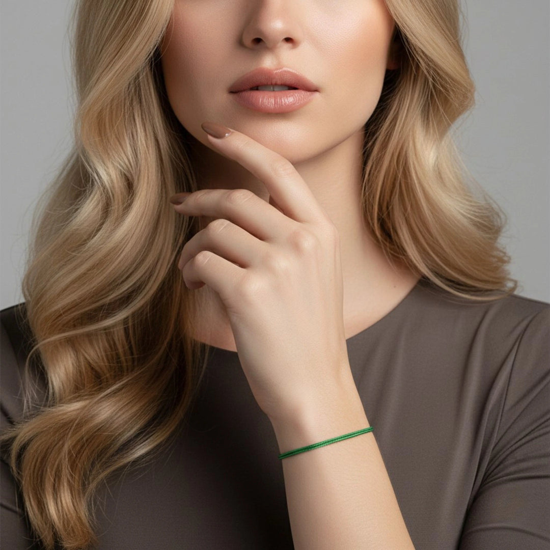 Woman with long blonde hair and a green bracelet on a neutral background