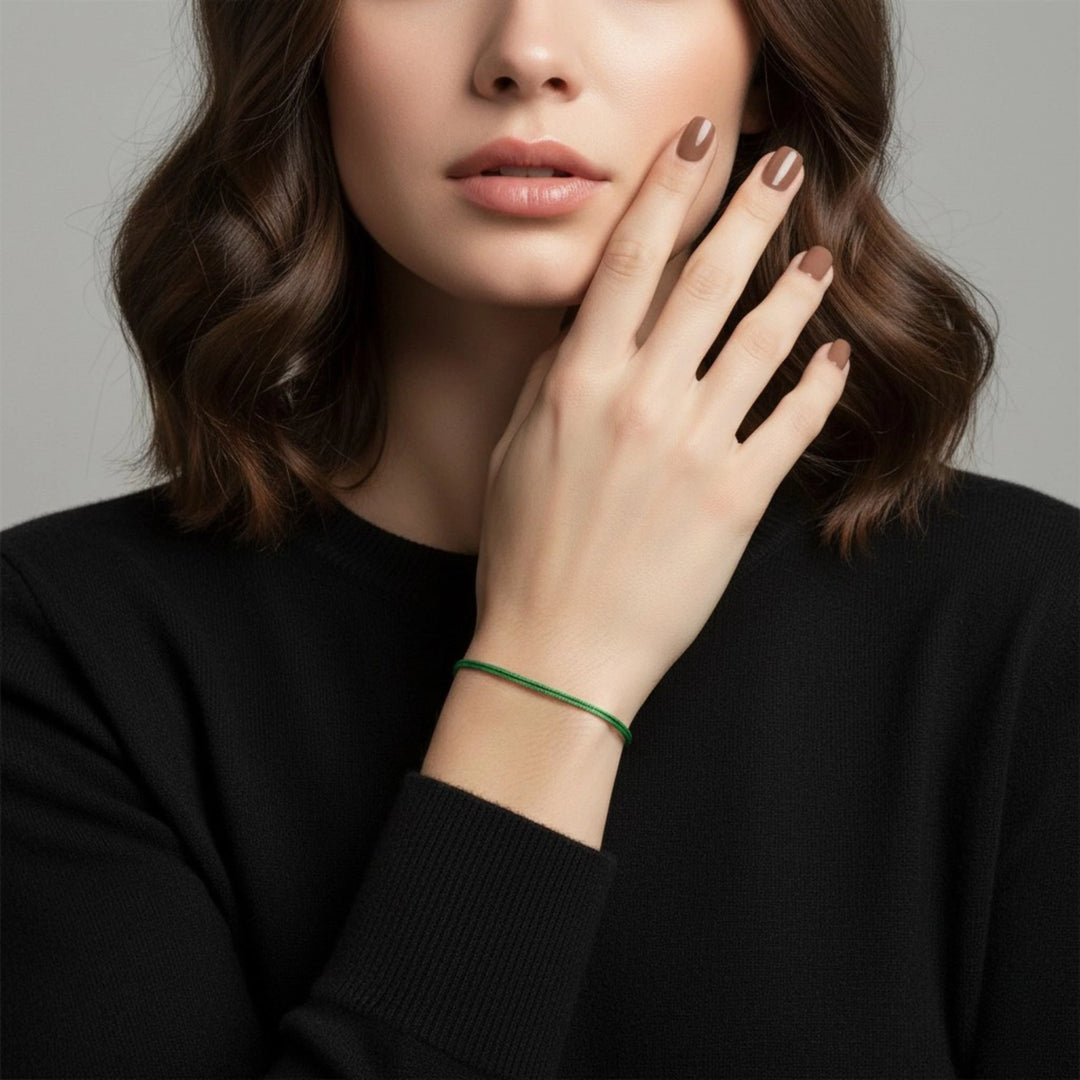 Woman wearing a green bracelet on a neutral background