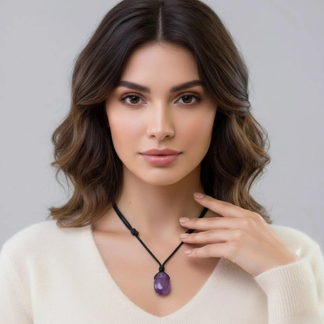 Woman wearing a necklace with a purple amethyst pendant against a neutral background