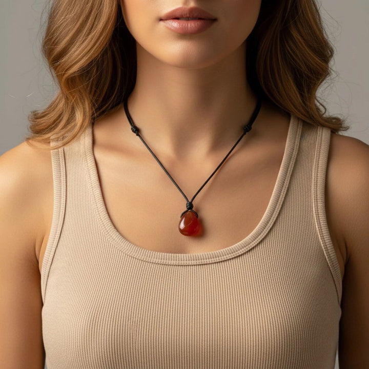 Woman wearing a beige tank top and a carnelian necklace with a red pendant.