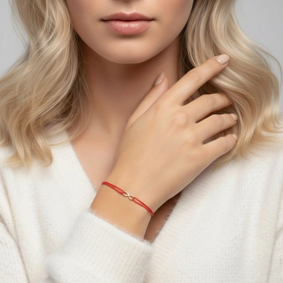 Close-up of a person wearing a red infinity  bracelet with a neutral background