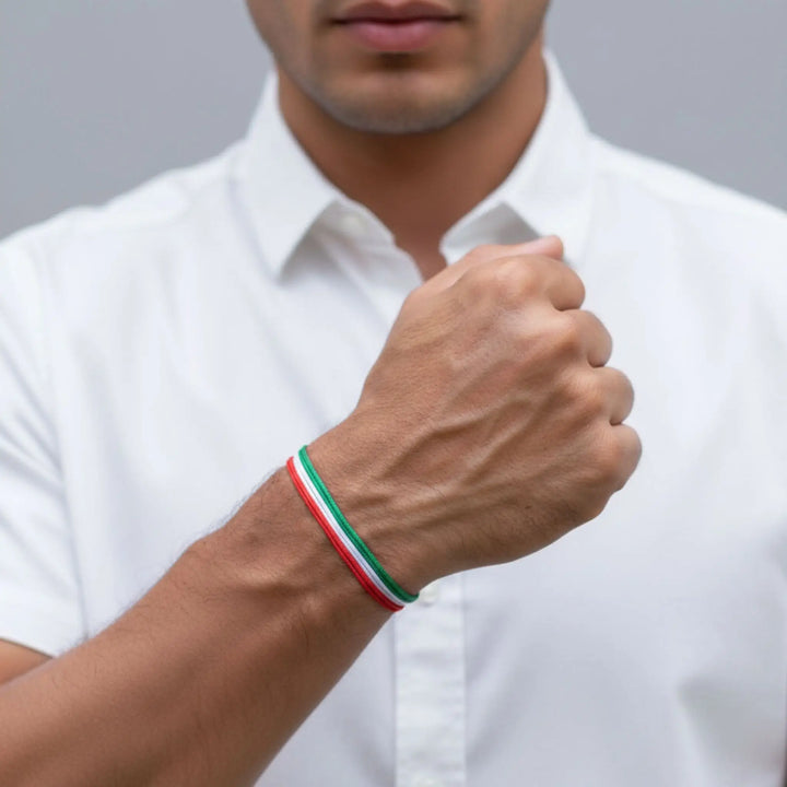 Person wearing a white shirt with a red, green, and white bracelet on a gray background