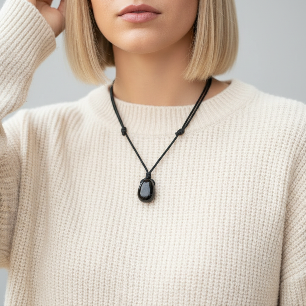 Person wearing a black jet pendant necklace with a plain background
