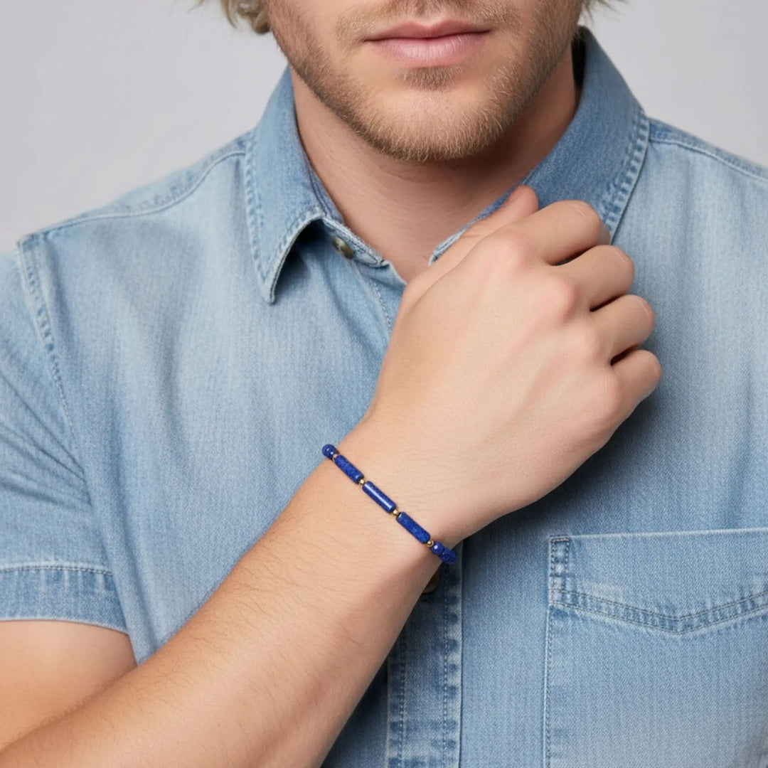 Man wearing a lapis lazuli blue bracelet on his wrist, with a plain background