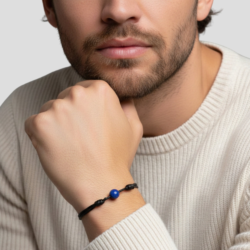 Man wearing smooth lapis lazuli single bead bracelet on black waxed nylon cord.
