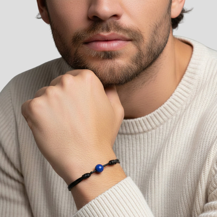 Man wearing smooth lapis lazuli single bead bracelet on black waxed nylon cord.
