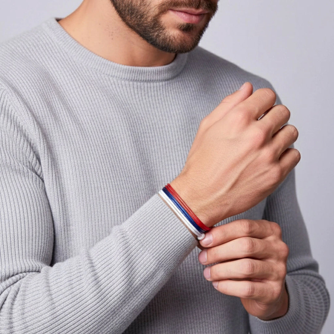 Man wearing a gray sweater with a colorful bracelet on a plain background