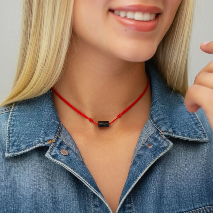 Woman wearing a red necklace with a black tourrmaline bead, smiling.