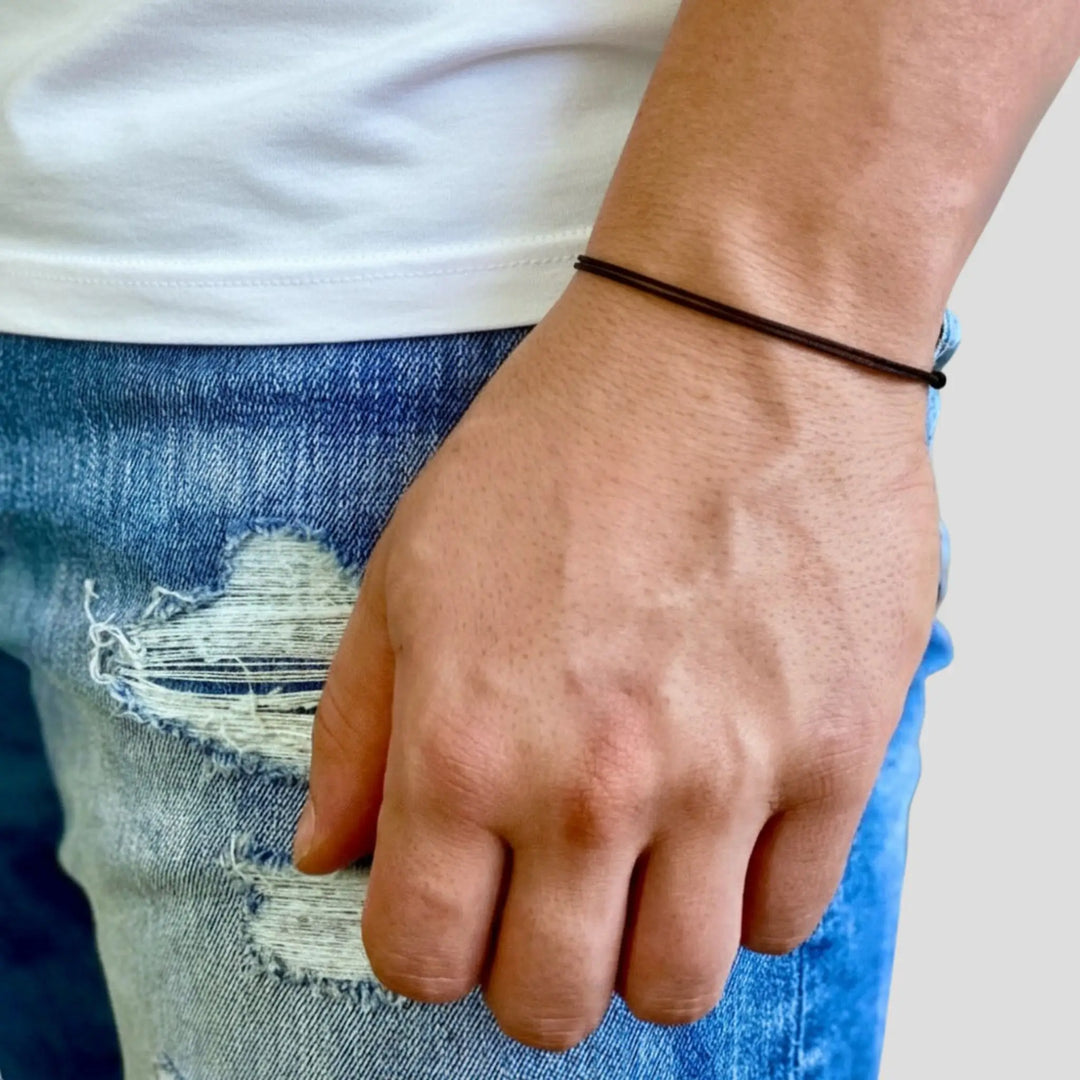 Hand wearing a black bracelet with a blurred background