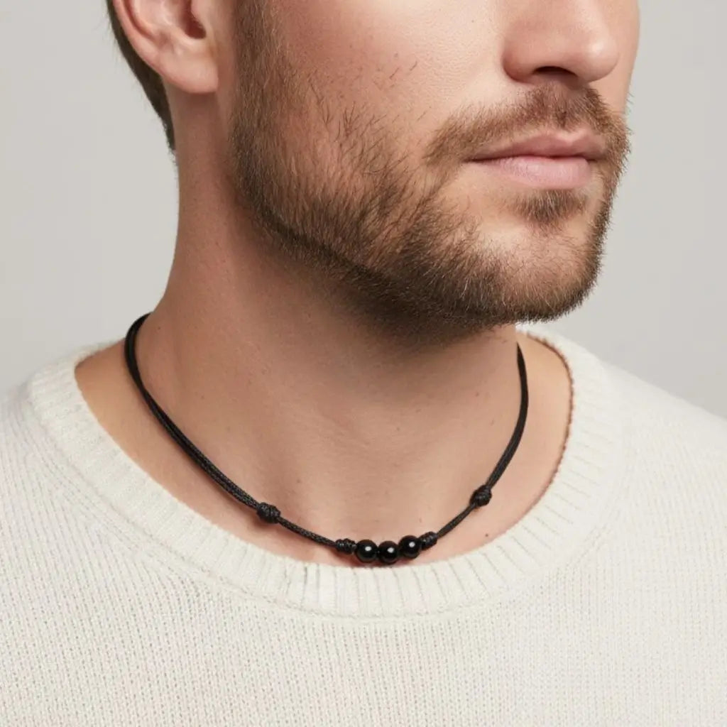 Man wearing a black tourmaline beaded necklace against a neutral background