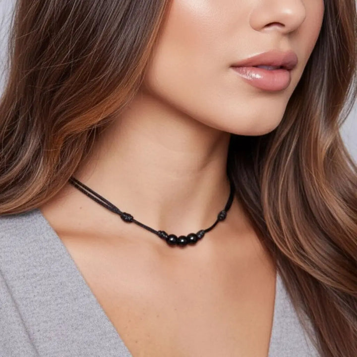 Woman wearing a black tourmaline beaded necklace with a neutral background