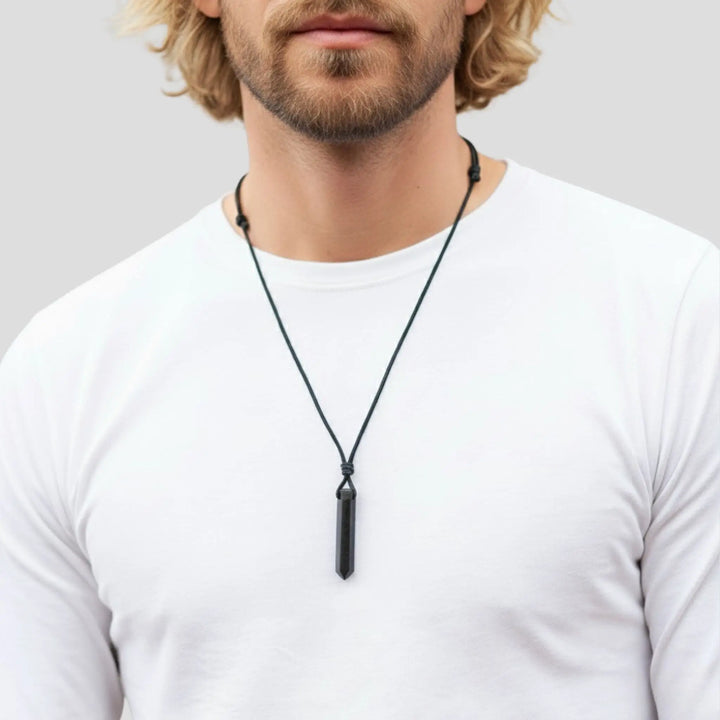 Man wearing a black tourmaline pendant necklace on a plain background