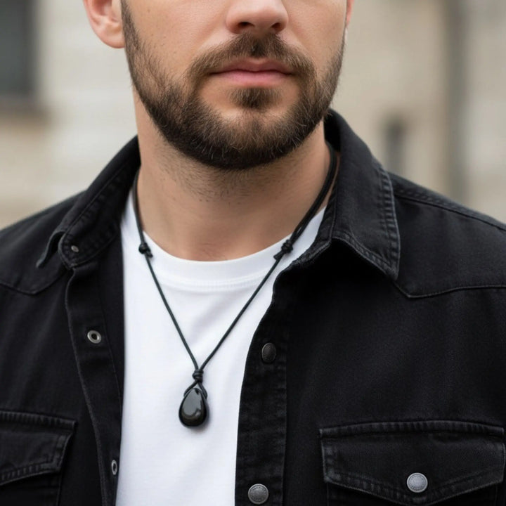 Man wearing a black tourmaline necklace with a blurred background