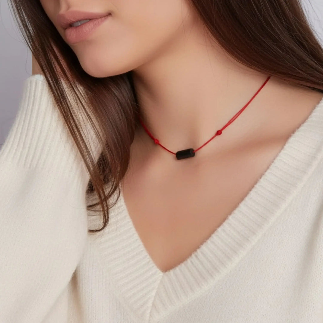 Close-up of a person wearing a red string black tourmaline necklace 