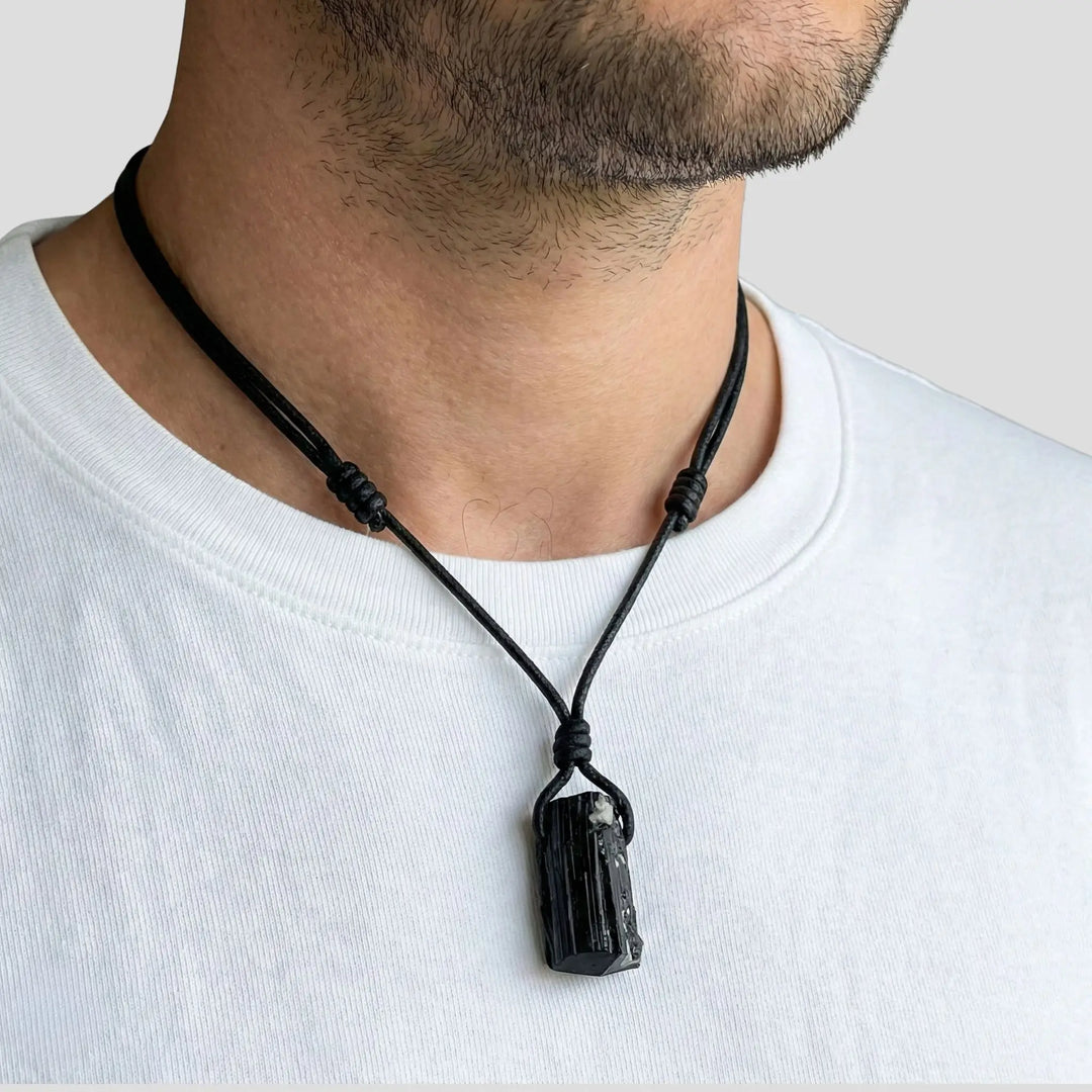 Black pendant necklace on a person wearing a white shirt