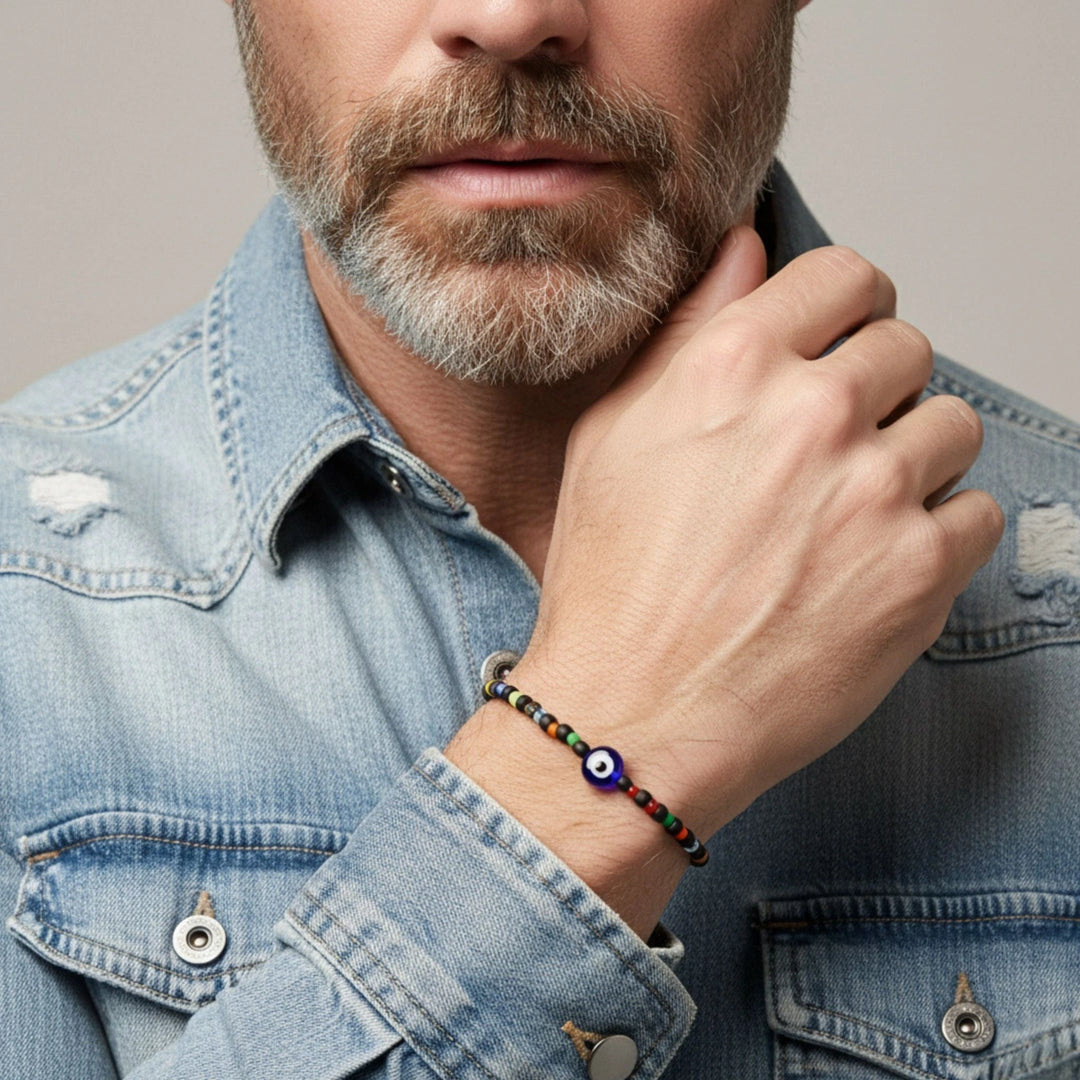Man wearing a bracelet with an eye charm on a neutral background