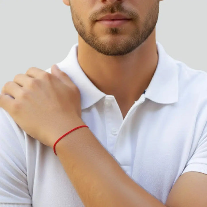 Man wearing a white polo shirt with a red string bracelet with a blurred background