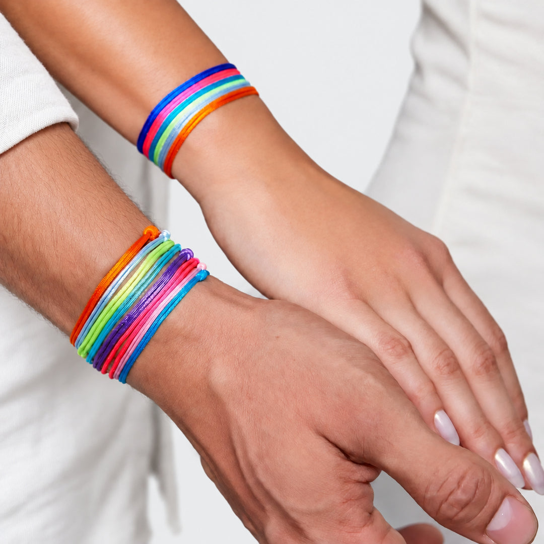 Couple wearing colorful nylon cord bracelets with adjustable knots, with the woman's hand resting on the man's hand.
