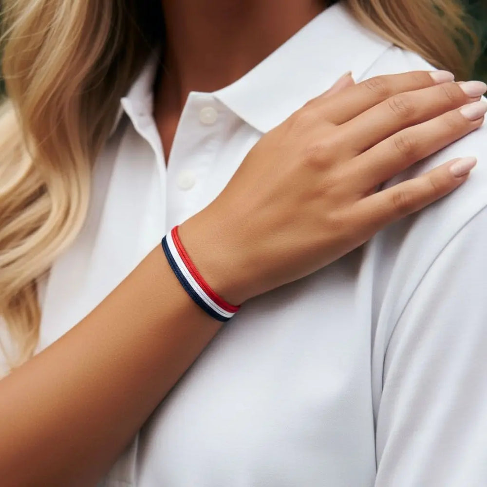 Person wearing a white shirt with a red, white, and blue bracelet on a blurred background