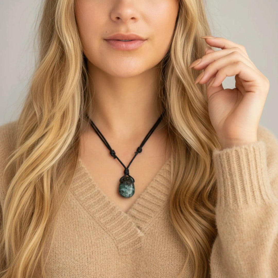 Woman wearing a necklace with a green emerald pendant against a neutral background