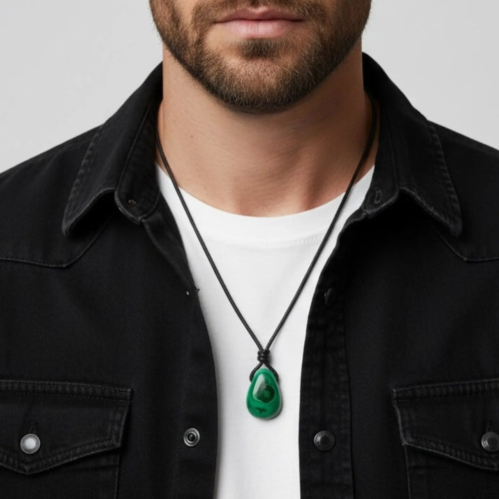 Man wearing a black jacket and white shirt with a green malachite pendant necklace.