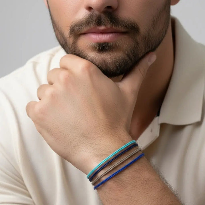 Man wearing a bracelet with four cords on a neutral background
