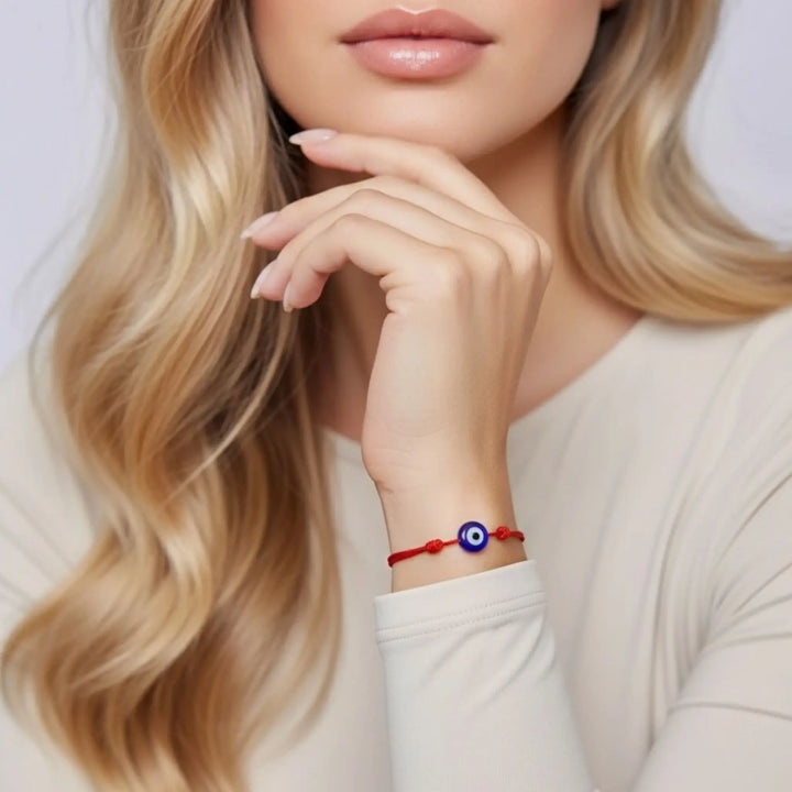 Close-up of a woman wearing a red bracelet with a blue and white evil eye design.