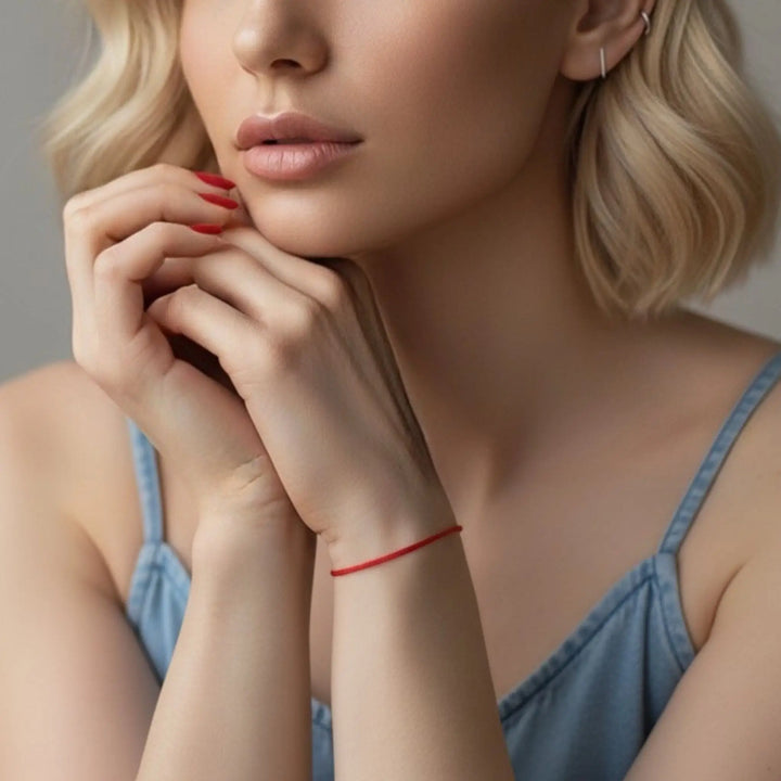 Close-up of a woman wearing a red bracelet on a neutral background