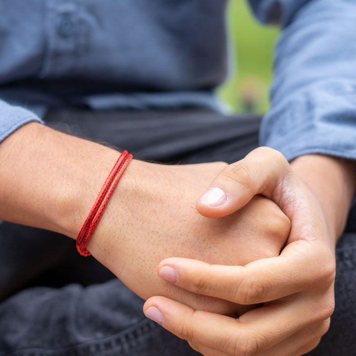 Close-up of a men wearing a red thick bracelet 