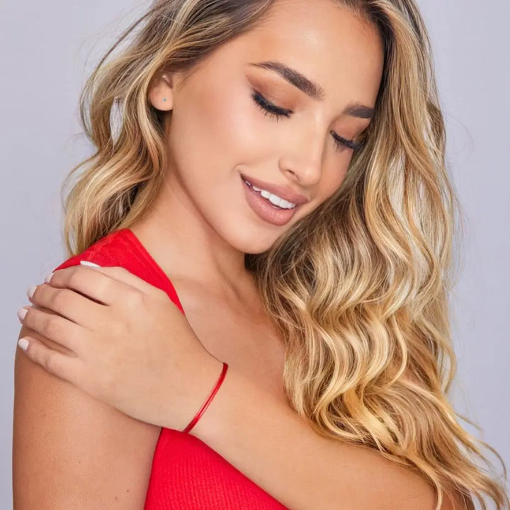 Close-up of a woman wearing a red bracelet on a plain background