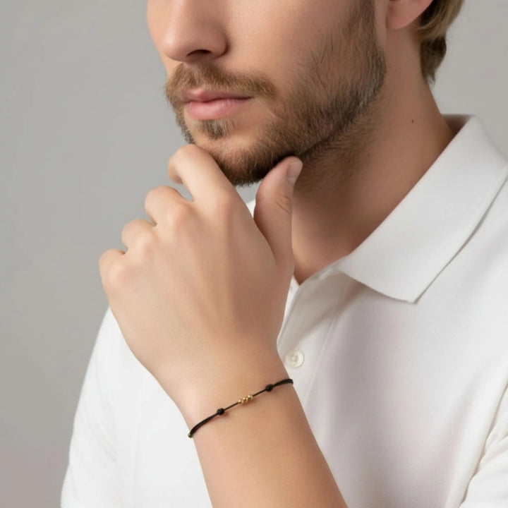 Man wearing a black bracelet on his wrist with a neutral background