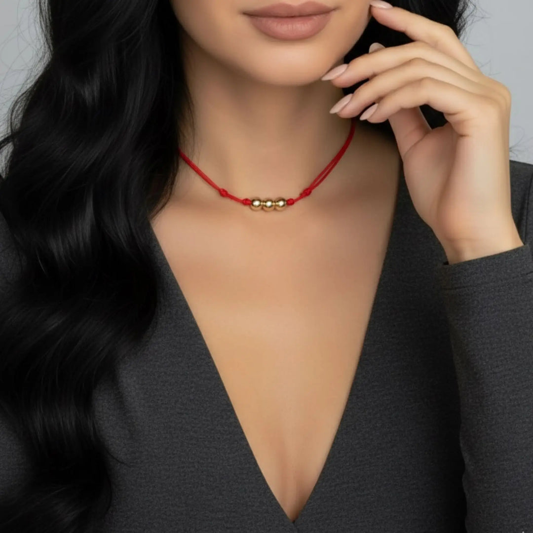 Woman wearing a red necklace with gold beads against a neutral background